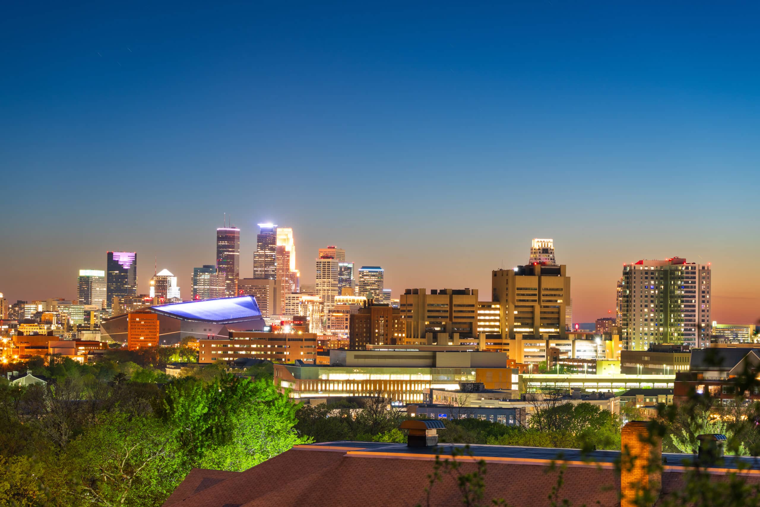 Downtown Minneapolis skyline with Target Field visible, Elite Party Bus ready for Twins game group transportation