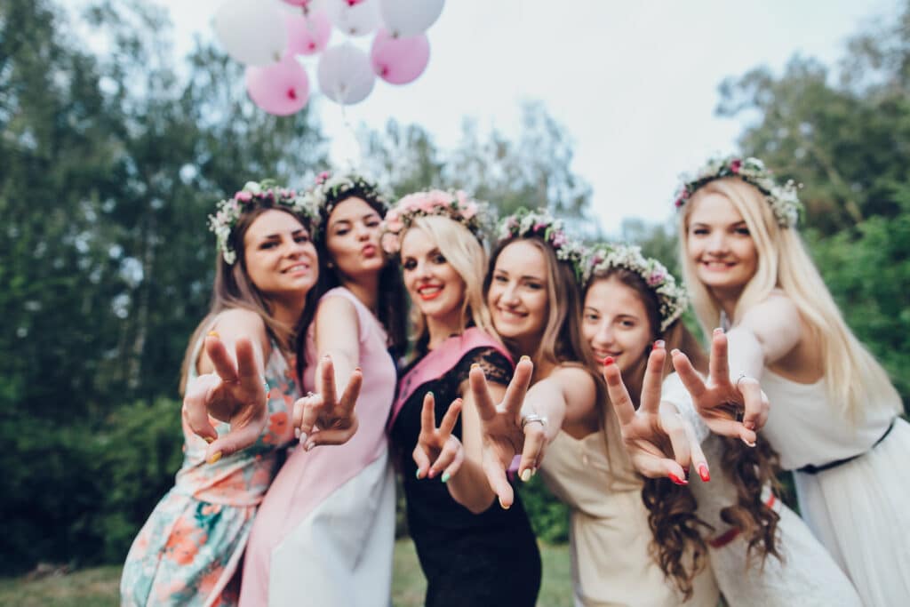 Group of smiling women in flower crowns holding balloons for bachelorette party boarding Elite Party Bus in Minneapolis